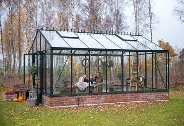 Stort drivhus på mur som gir følelsen av et lite hus i hagen som kan brukes på mange forskjellige måter.