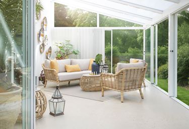 Miljøbilde av Sunflower loungesett med hev- og senkbart sofabord. Loungesettet er plassert i et uterom med en vakker grønn hage i bakgrunnen.